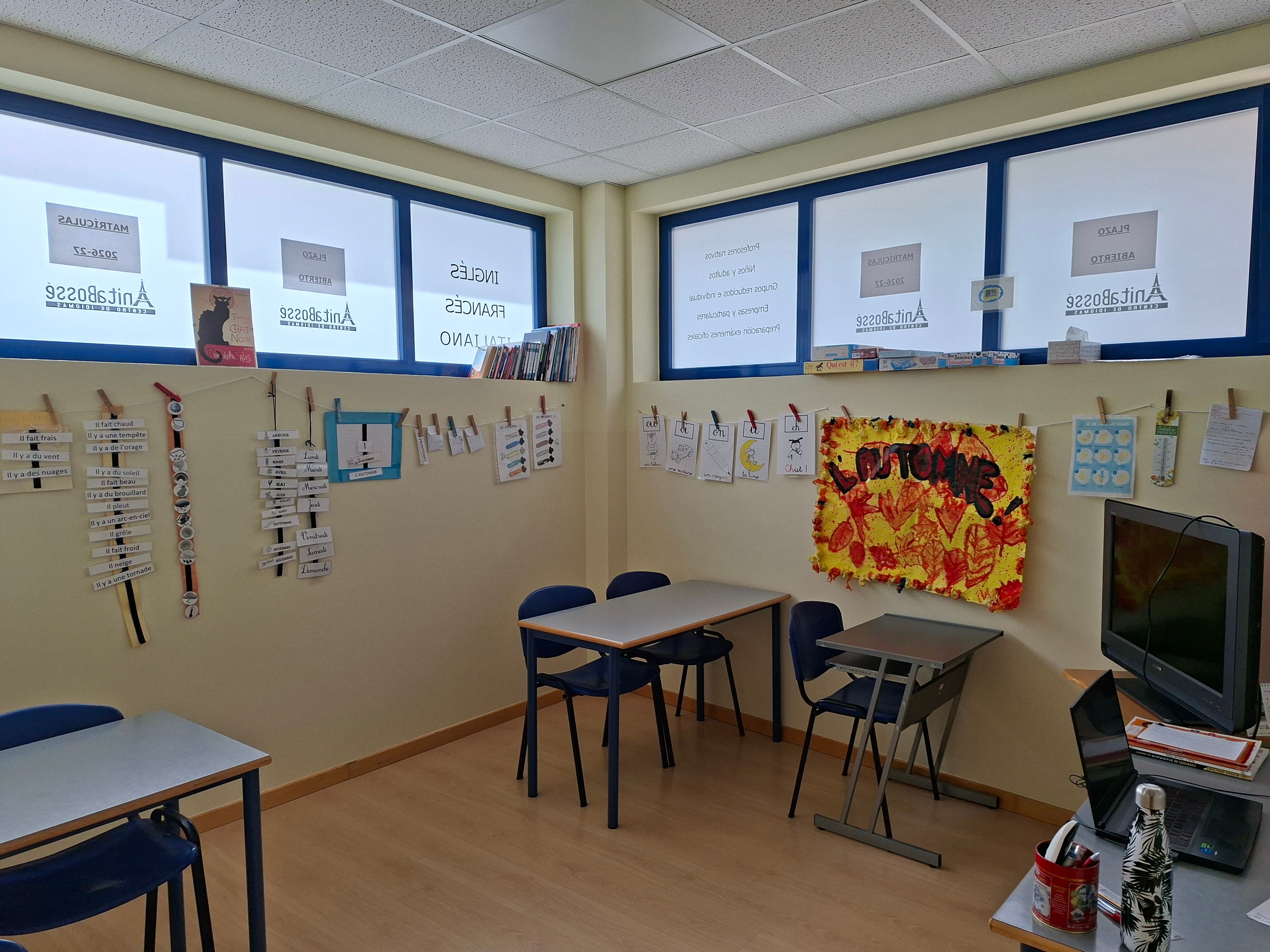 Aula con las mesas en grupo y un calendario en francés colgado con pinzas en la pared