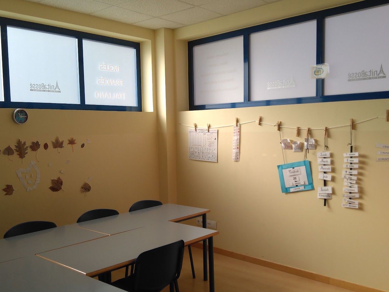 Aula de francés con las mesas en grupo y el calendario colgado con pinzas en la pared